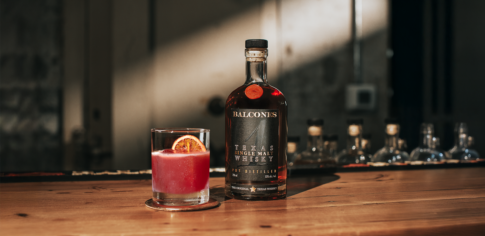 Bottle of Texas 1 Single Malt Whisky with A Cardinal's Message cocktail on a table.