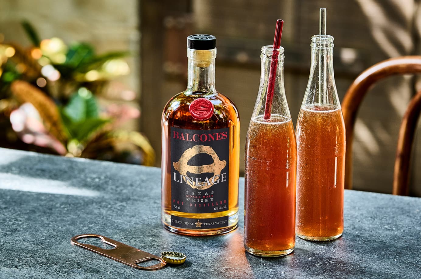Bottle of Lineage Texas Single Malt Whisky with two glasses of Balcola cocktails on table
