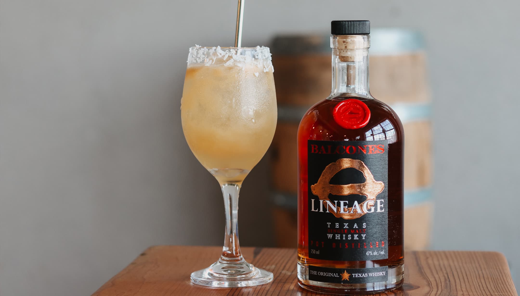 Bottle of Lineage Texas Single Malt Whisky with a glass of DAWN FLAMINGO cocktails on table