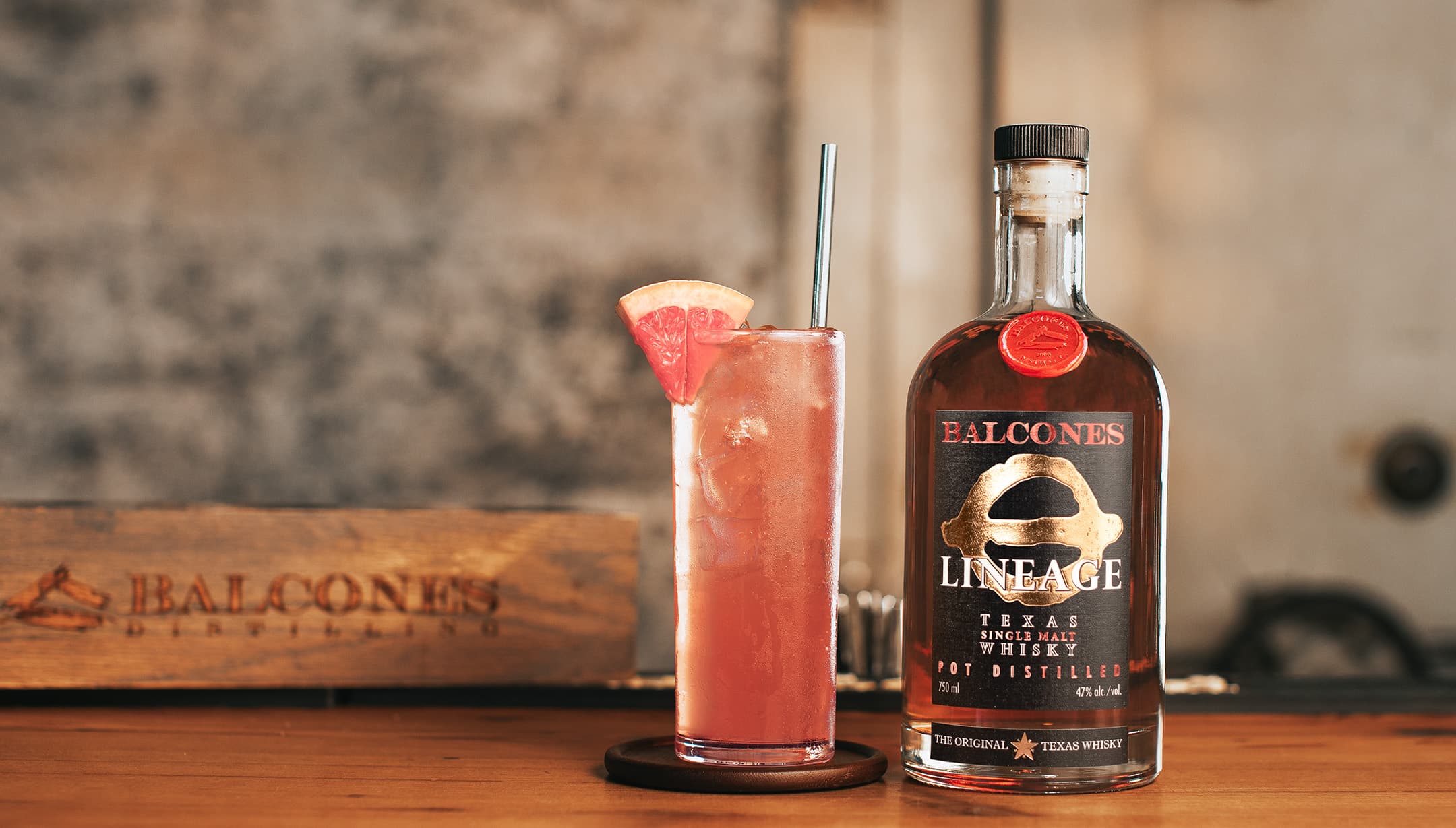 Bottle of Lineage Texas Single Malt Whisky with a glass of Grapefruit Highball cocktails on table