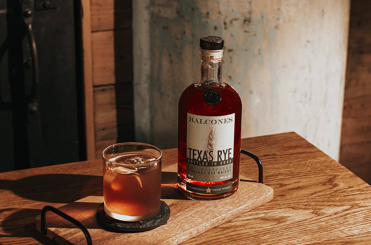 Bottle of Baby Blue with a glass of Baby Blue paloma cocktails on table