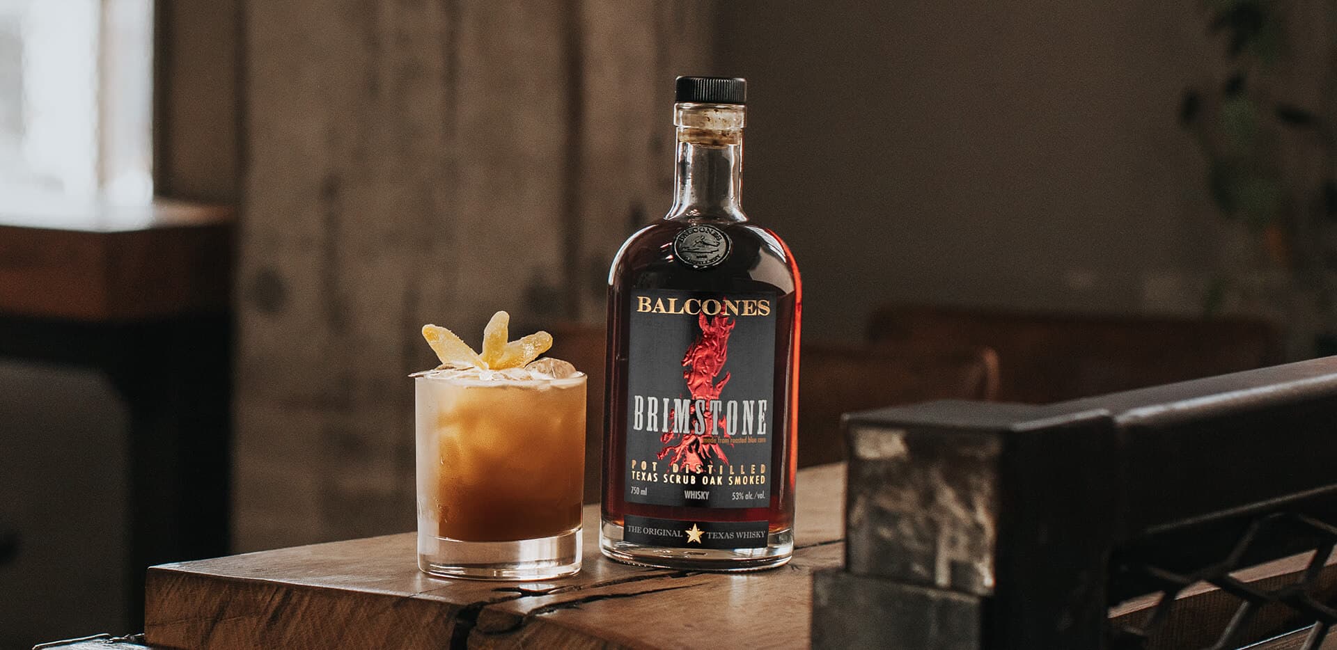 A bottle of Brimstone Smoked Whisky with a Texas Chillin' cocktail on a table.
