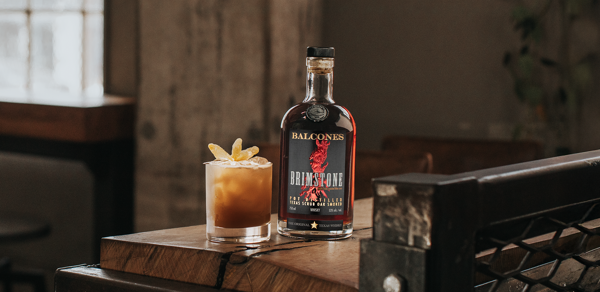 A bottle of Brimstone Smoked Whisky with a Texas Chillin' cocktail on a table.