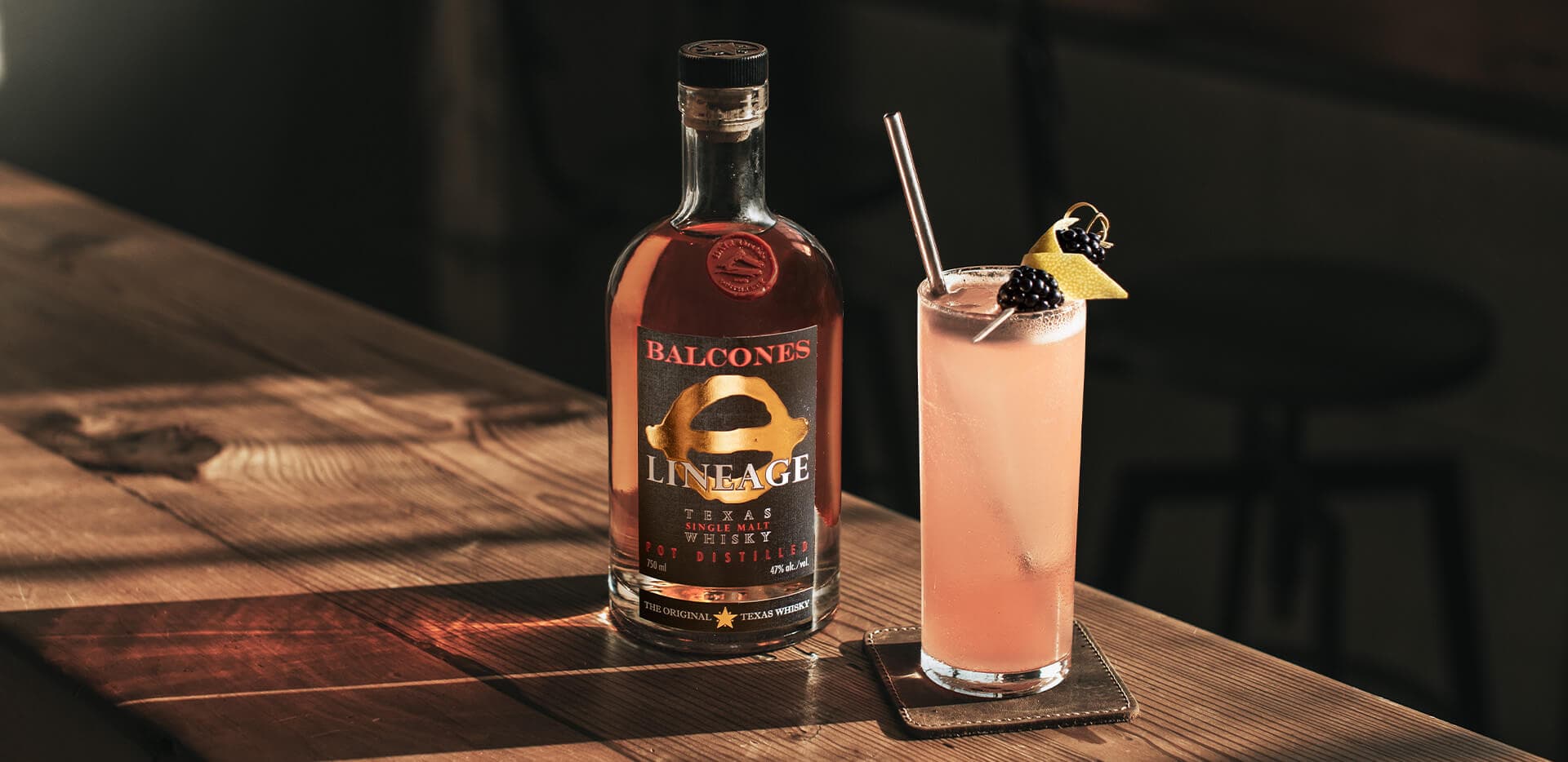A bottle of Lineage Texas Single Malt Whisky with an Under the Elder Tree cocktail on a table.