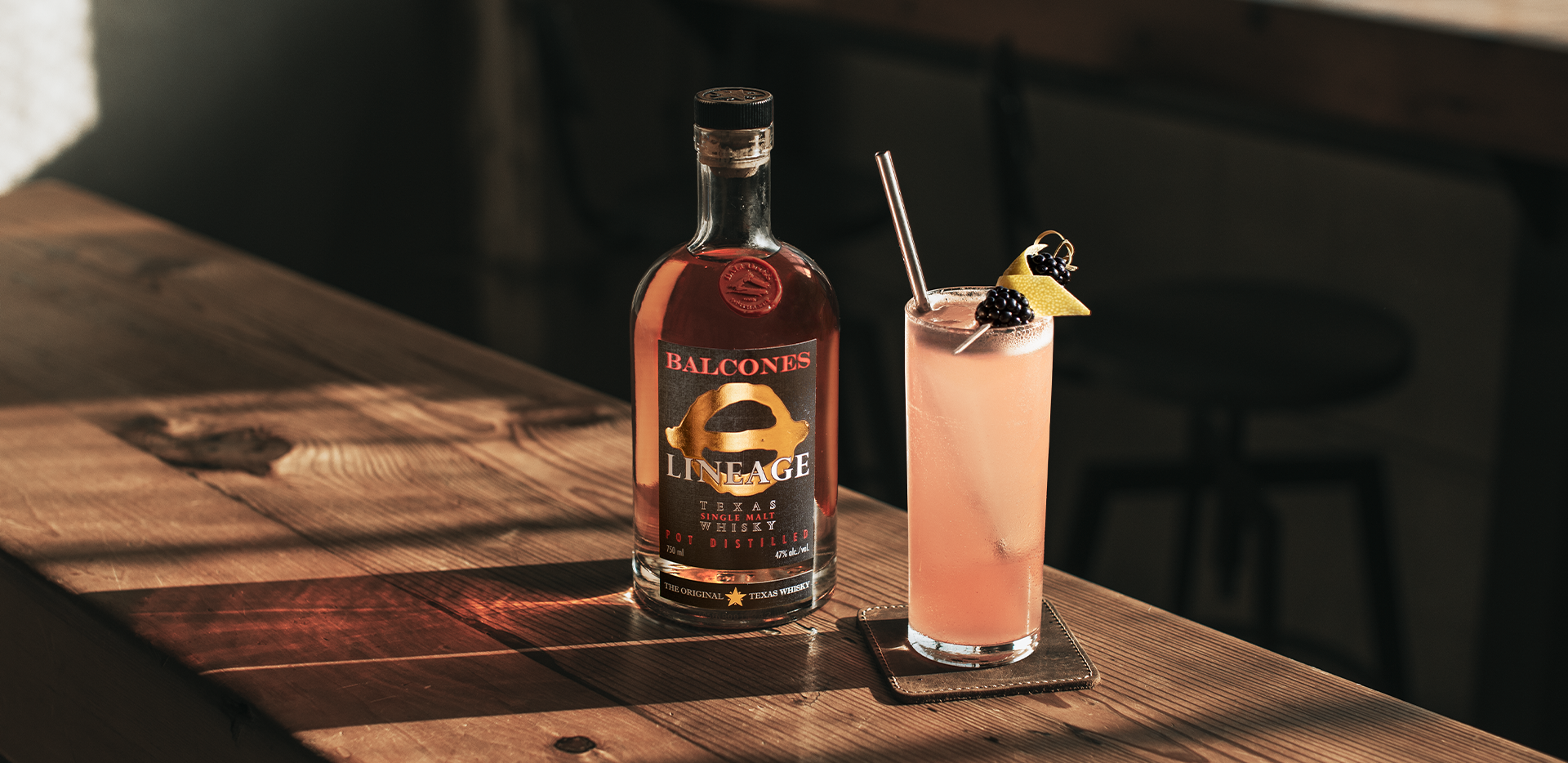 A bottle of Lineage Texas Single Malt Whisky with an Under the Elder Tree cocktail on a table.