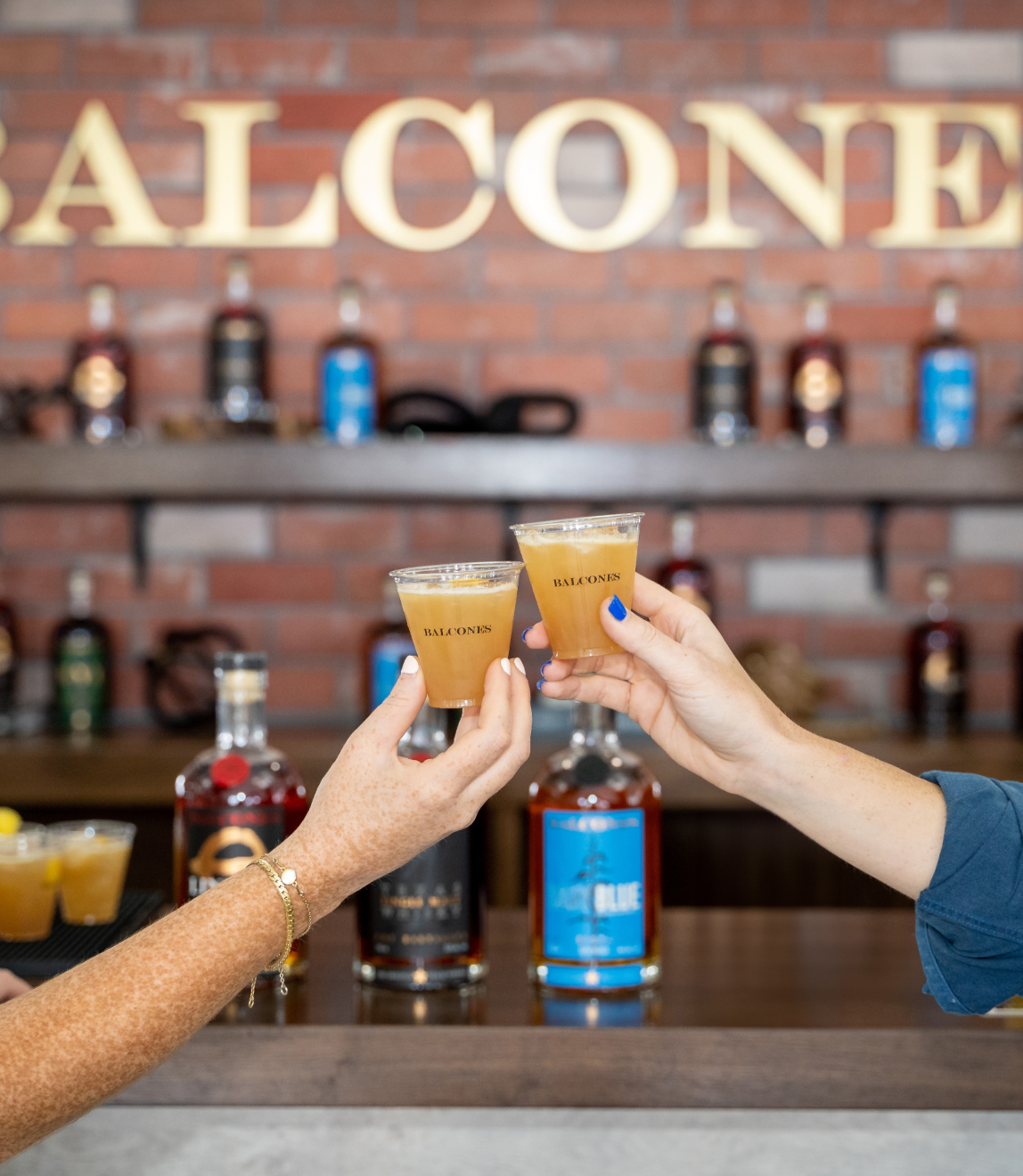 Two hands cheers'ing with Balcones' cocktails