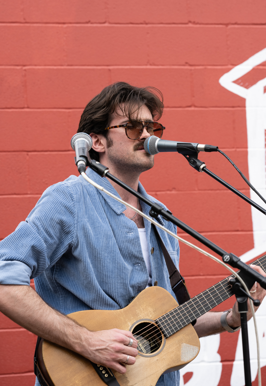Man singing into microphone and playing guitar on stage