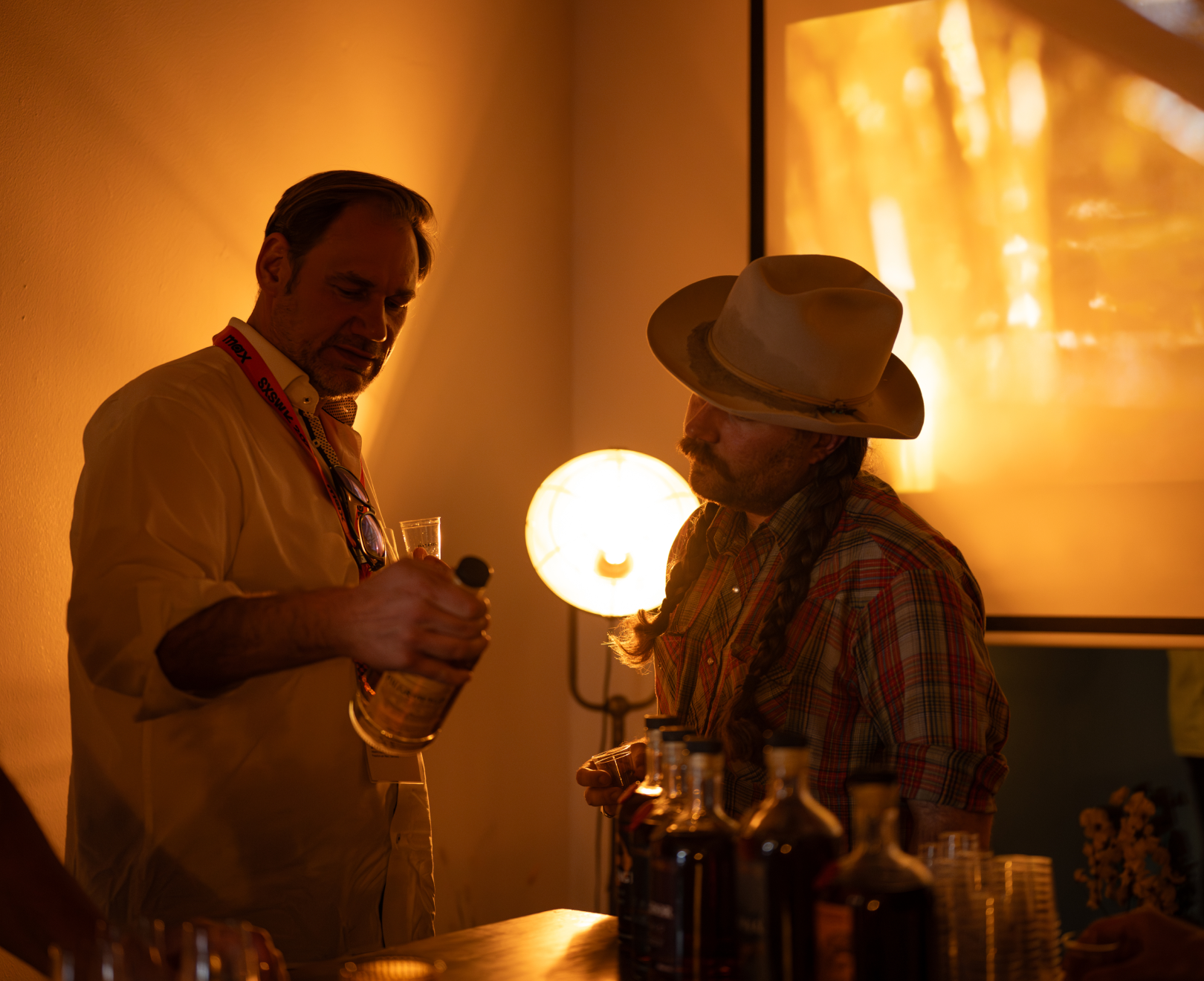 Two men talking holding a bottle of Balcones