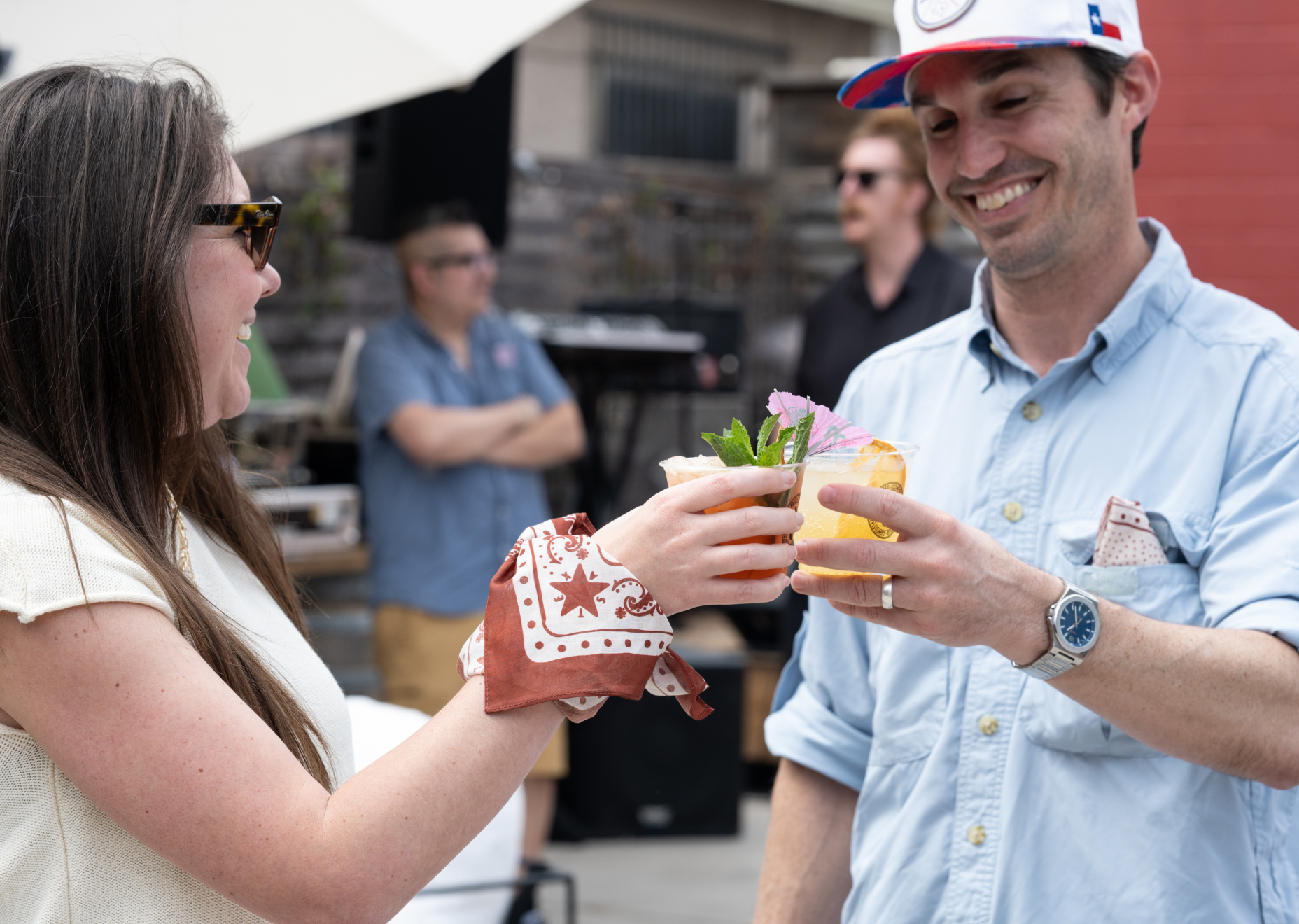 Two people cheers'ing and smiling with Balcones' cocktail