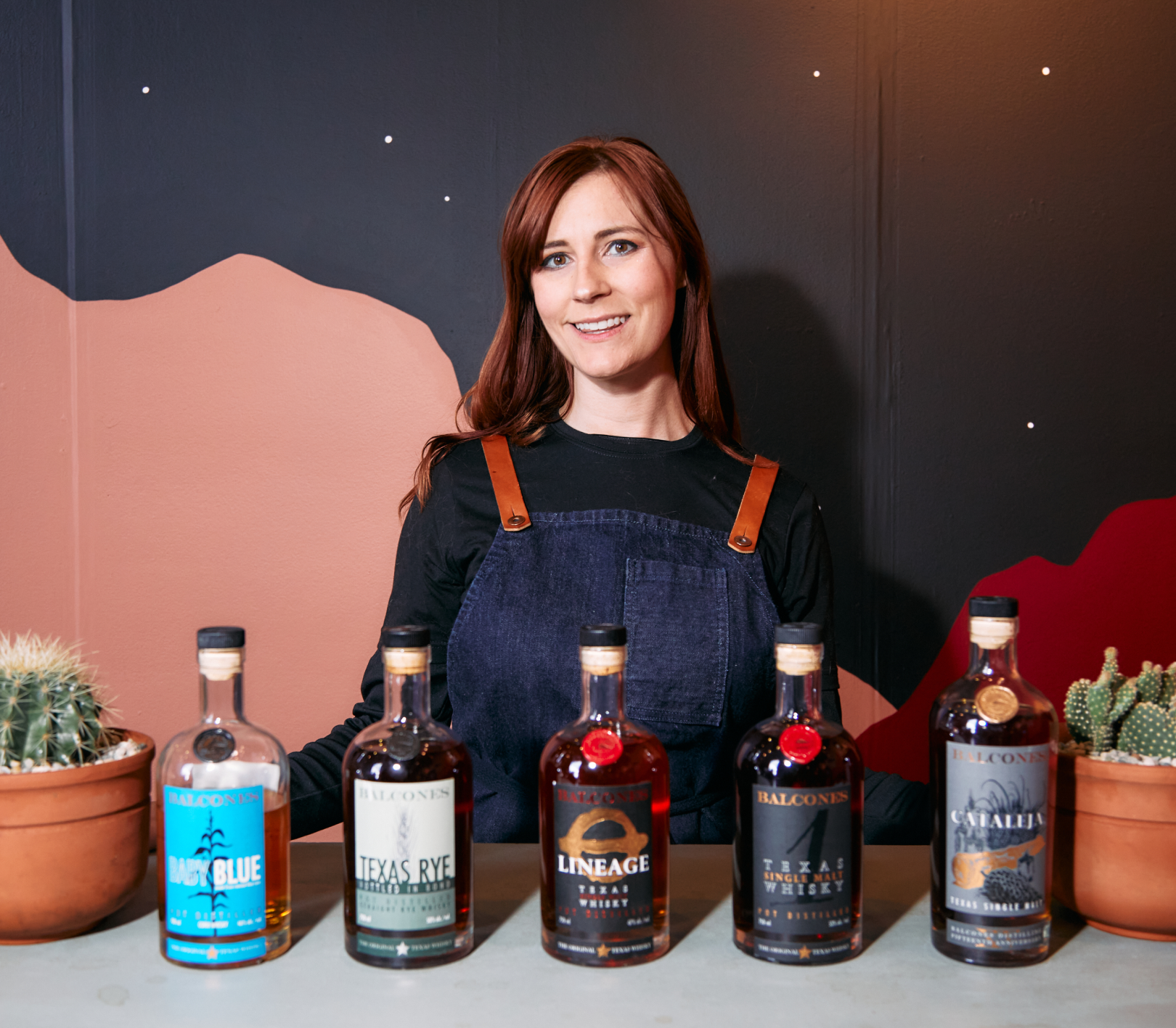 Bartender posting with five bottles of Balcones