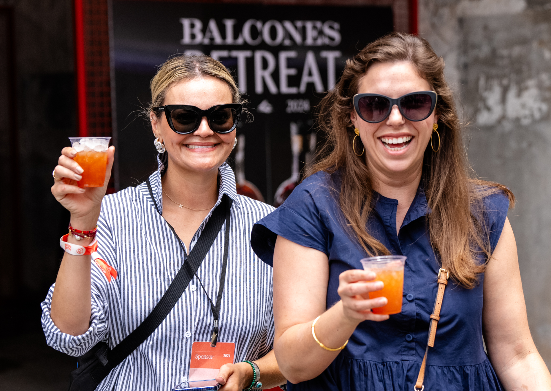 Two women holding cocktails and smiling at camera