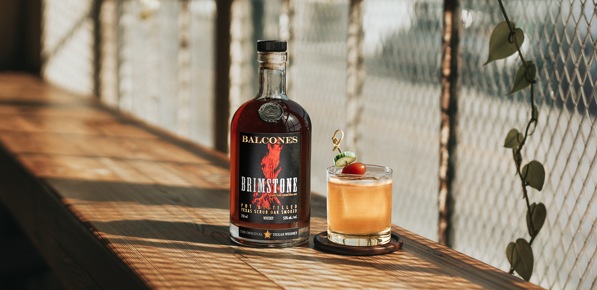 A bottle of Brimstone Smoked Whisky with a Garden Variety cocktail on a table.